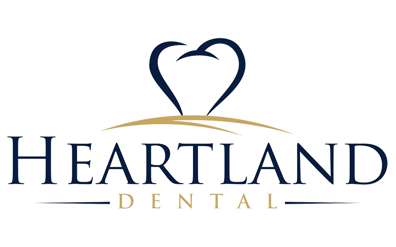 Heartland Dental logo featuring a stylized dark blue tooth icon over a gold curved line with dark blue and gold text.