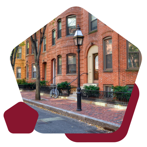 A street view of red brick brownstone buildings with a lamp post and a bicycle on a brick sidewalk.