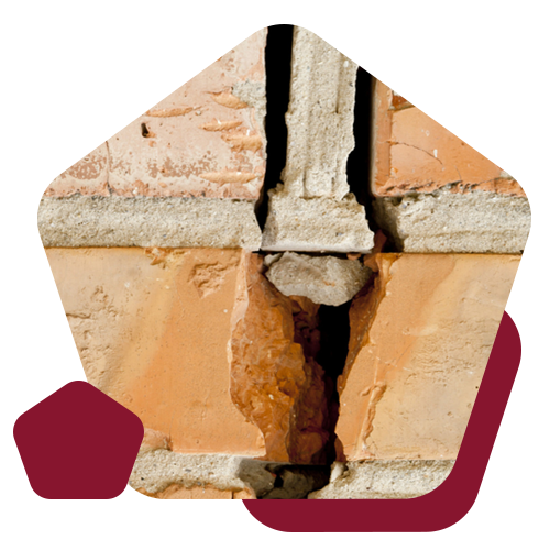 A close-up of a damaged brick wall with a large, vertical crack extending through multiple layers of mortar and brick.