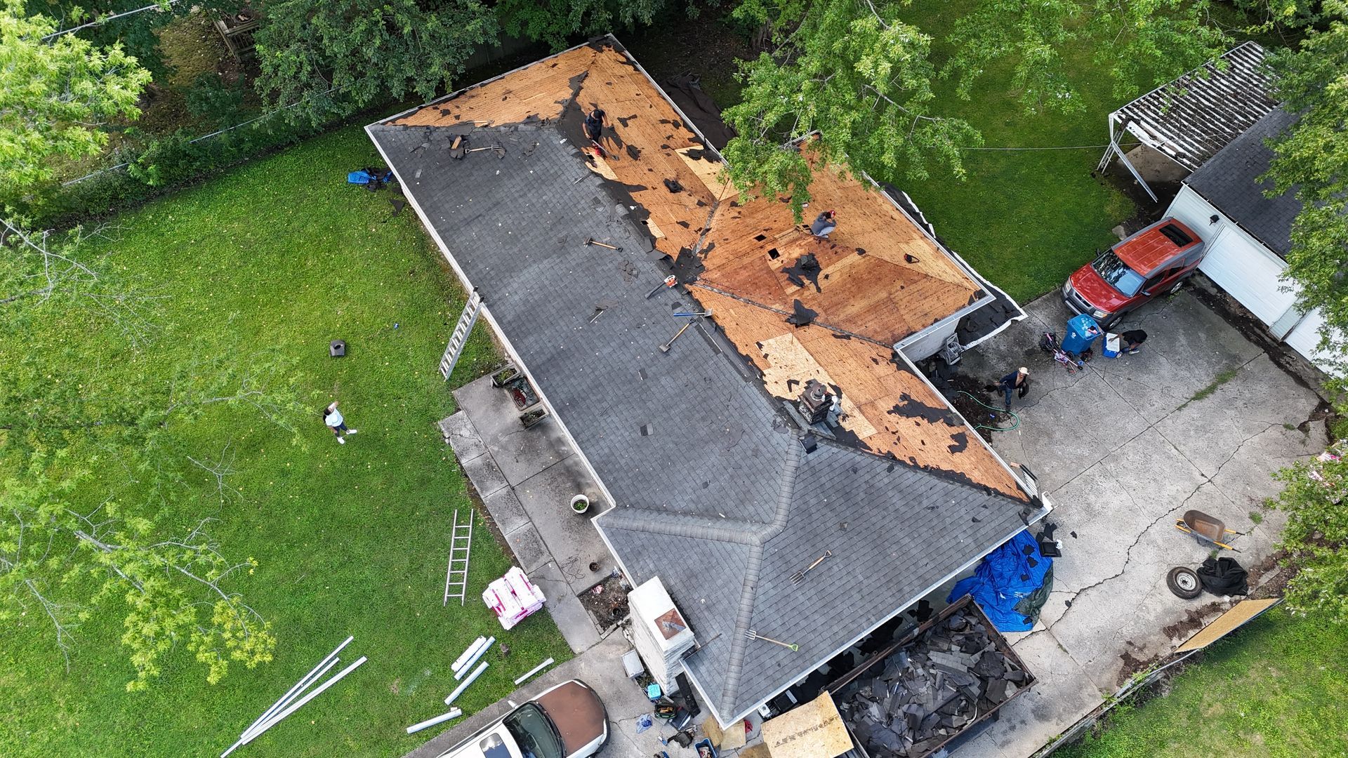 Aerial view of a residential roof under construction with sections of exposed wooden decking and old roofing material.