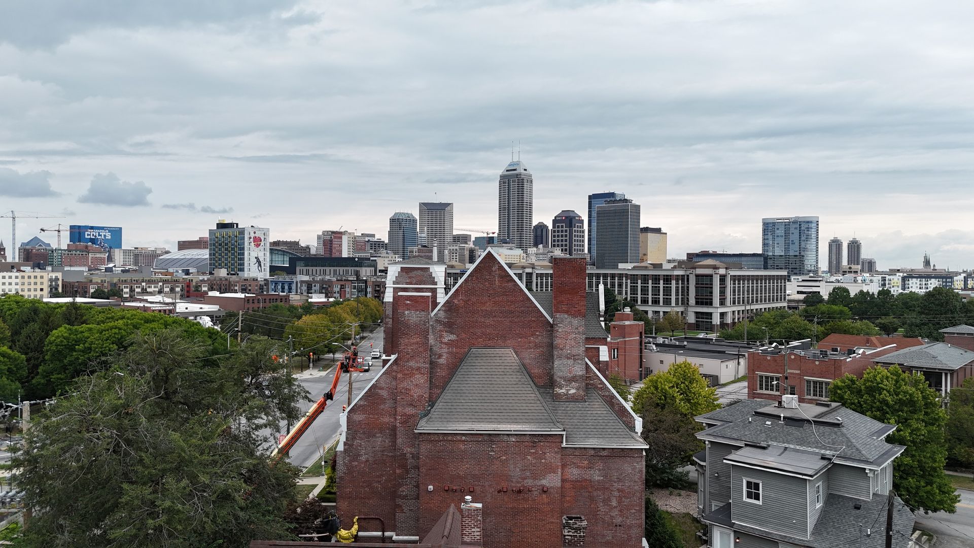 A view of the Indianapolis skyline behind a prominent brick church building and residential neighborhood.