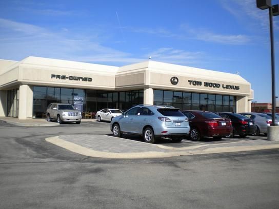 Exterior view of Tom Wood Lexus dealership with parked cars under a clear blue sky.